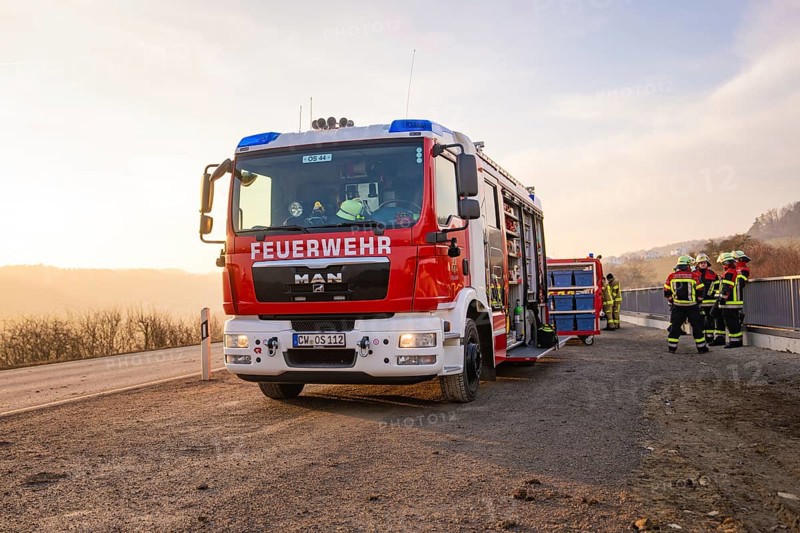 Firefighters stand by a fire truck on the side of the road at sunrise, ready for action, fire brigade exercise on the Hermann Hesse Railway, Ostelsheim, Calw district, Germany