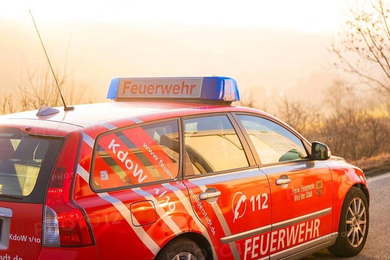 A red fire department car on a country road at sunset, fire department exercise on the Hermann Hesse railway, Ostelsheim, Germany