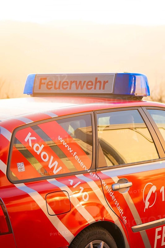 Red fire engine with blue signal light at dusk, fire department exercise on the Hermann Hesse railway, Ostelsheim, Germany