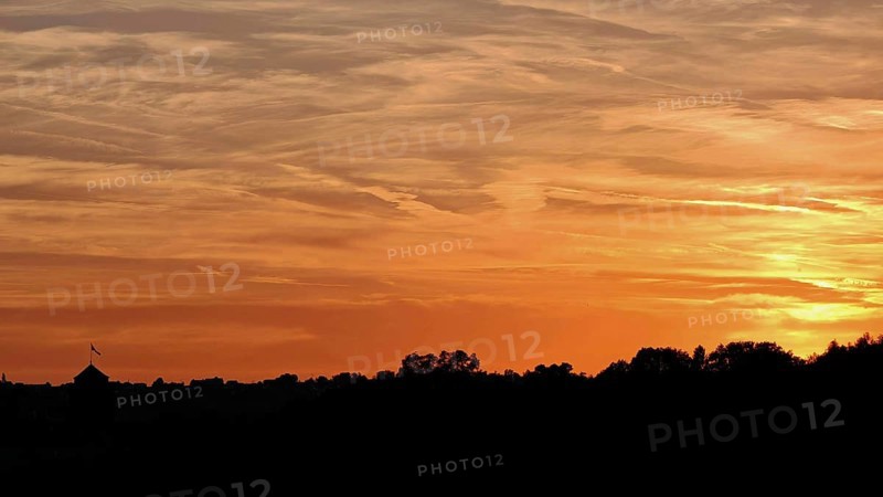 Beautiful sunset with orange sky over silhouettes of trees, Frankenwald nature park Park