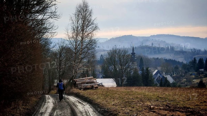 Rural trail leads to a small village with a church in the background, surrounded by hills, Thuringian Forest nature park Park