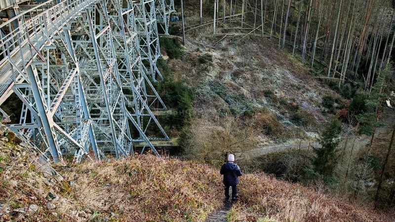 Hikers on a path next to a large metal-textured bridge, old railroad bridge in the forest, Ziemestalbrücke, Thuringian Forest