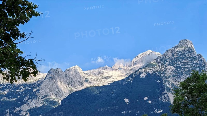 Mountains under clear blue sky, rocky peak in foreground, Slovenia