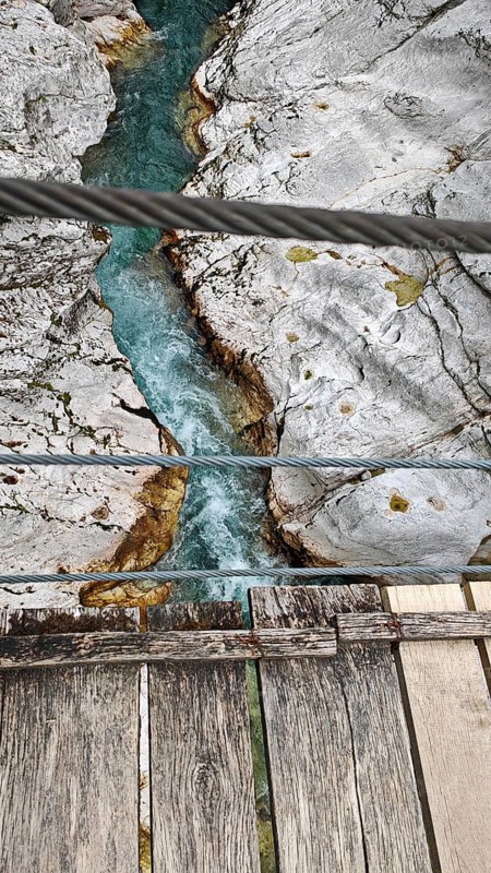 Wooden bridge over turquoise river between bright, rocky banks, Soca Valley, Slovenia