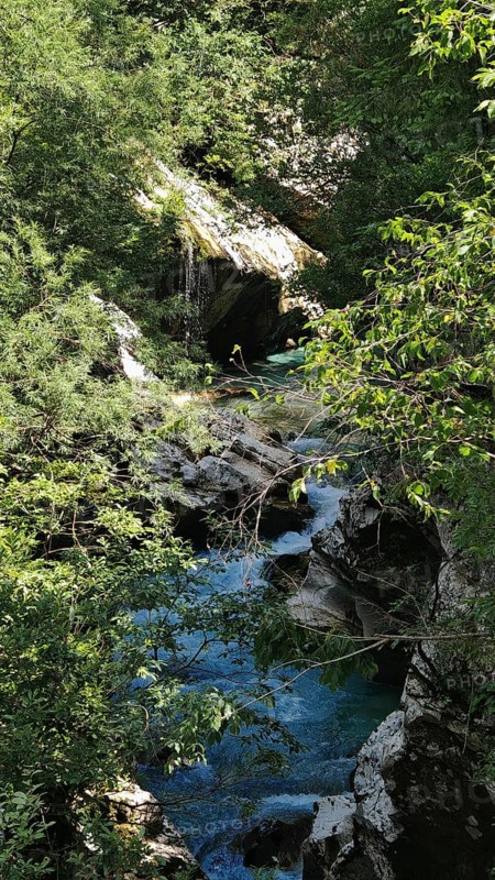 Small waterfall surrounded by green trees and rocks, a quiet natural setting, Soca Valley, Slovenia