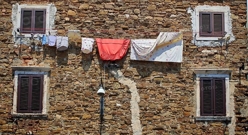 Rustic stone façade with hanging linen and several dark windows, Slovenia