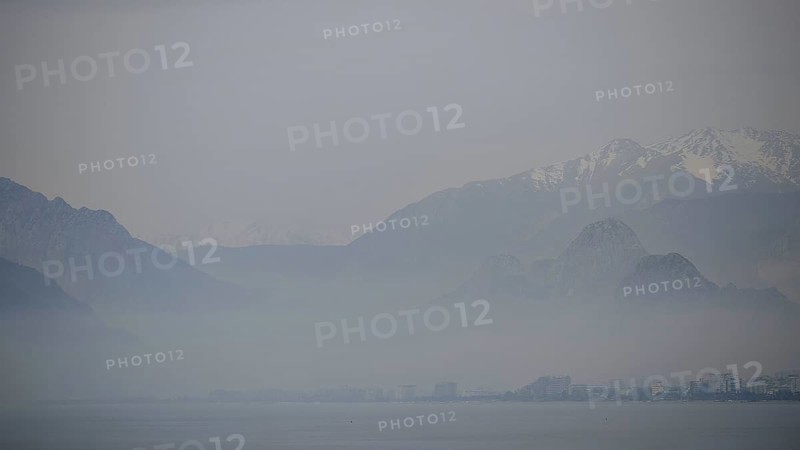 Blurred mountains rise above the misty sea under a grey sky, Antalya, Turkey