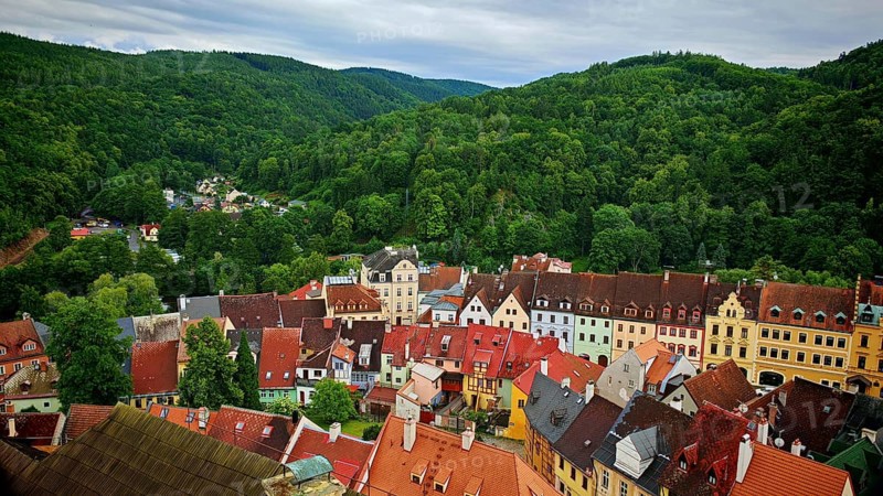 Panorama of a city with colorful roofs surrounded by wooded hills, view of Loket from above, Czech Republic