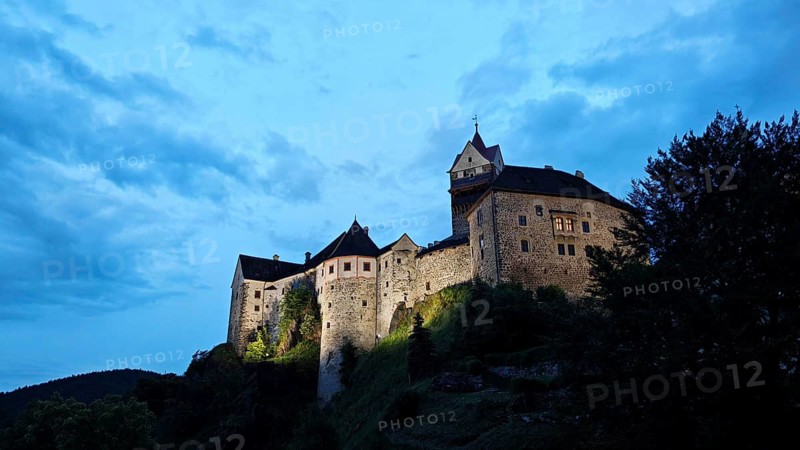 Illuminated castle at dusk against a blue sky, Loket, Czech Republic