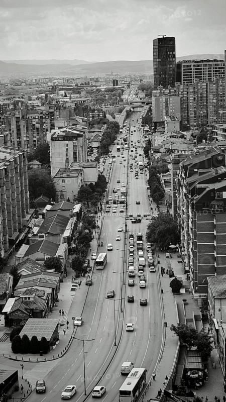Urban scene with a long busy street lined with tall buildings in black and white, Pristina, Kosovo