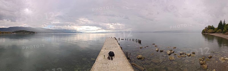 Panoramic picture of a long jetty over a wide, calm lake, Lake Ohrid, North Macedonia