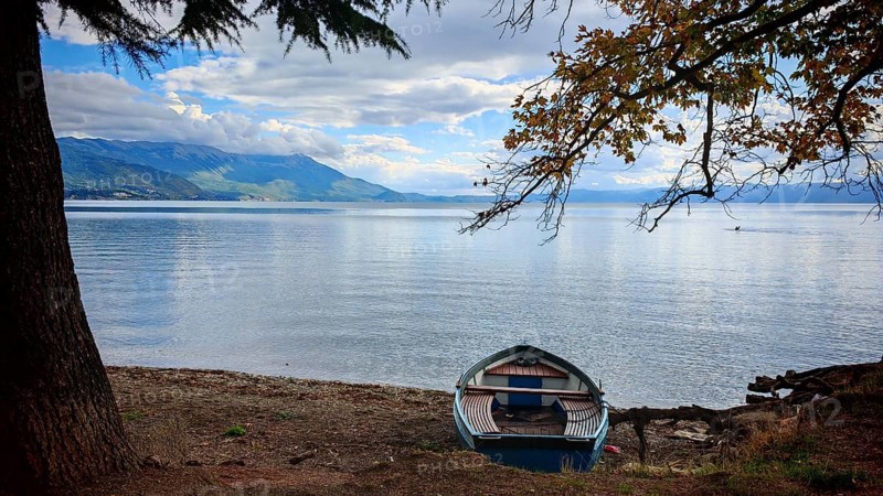 A boat is quietly lying on the shore of a lake with autumn colors, Lake Ohrid, North Macedonia