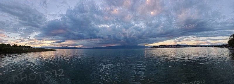 Panoramic view of a lake surrounded by dramatic clouds at sunset, Lake Ohrid, North Macedonia