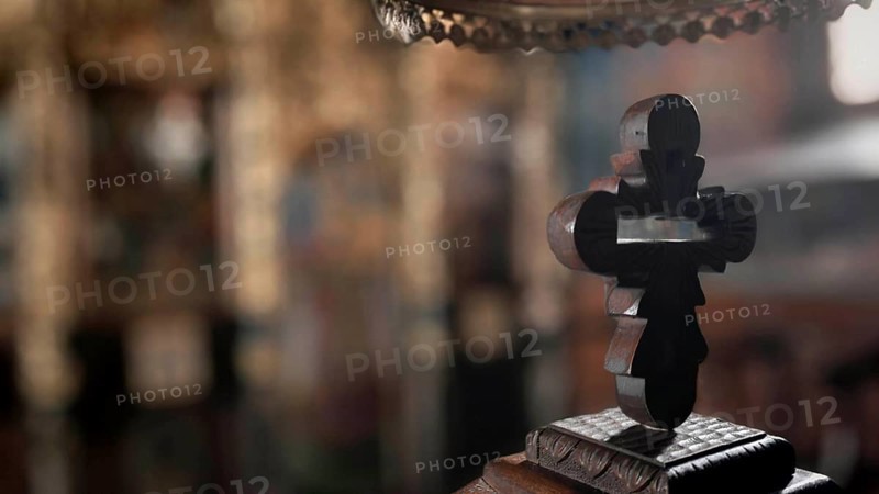 An intricately carved wooden cross against a blurred church background with mystical reflections, Ohrid, North Macedonia