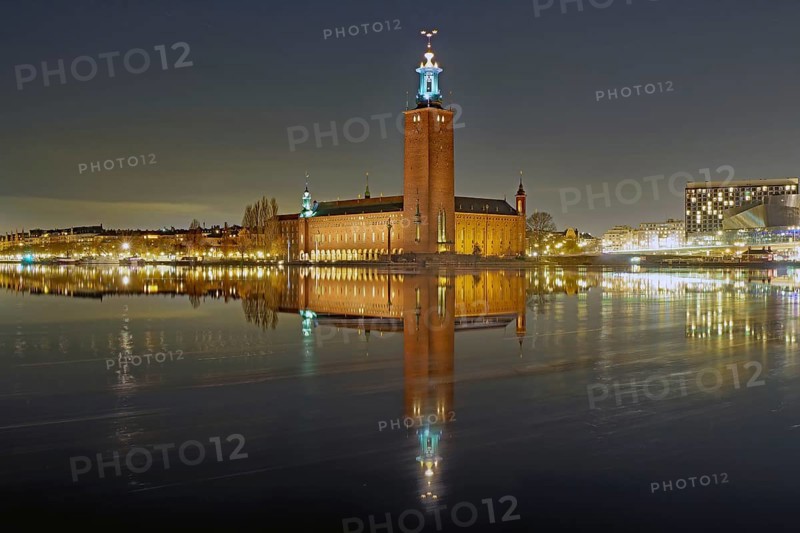 Night scene of a town hall with illuminated tower, peaceful reflection on calm water, Nobel Prize, City Hall, Stockholm, Sweden