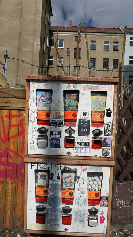 Colourfully glued chewing gum machine on a wall in an urban environment, Berlin