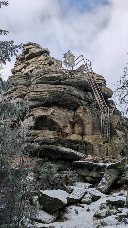 Rock formation with metal stairs in snow surrounded by a wintry sky, Fichtelgebirge