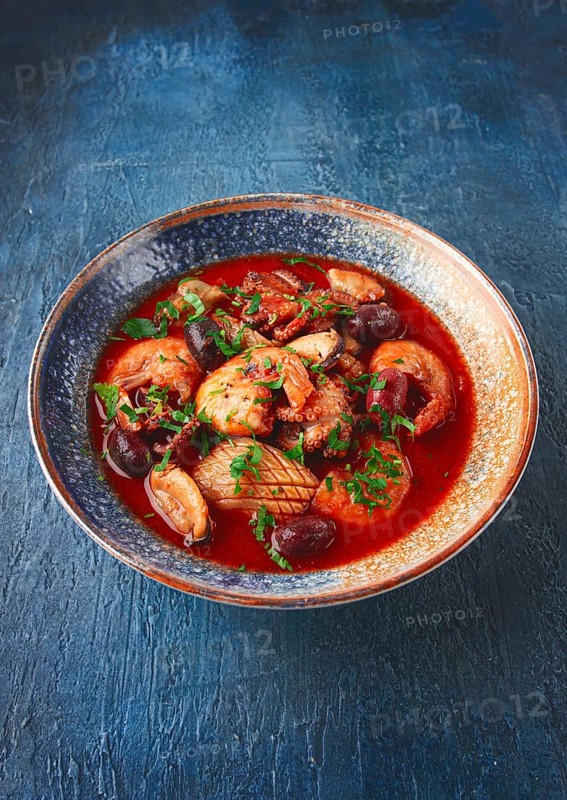 Seafood in tomato sauce with olives, on a dark blue background