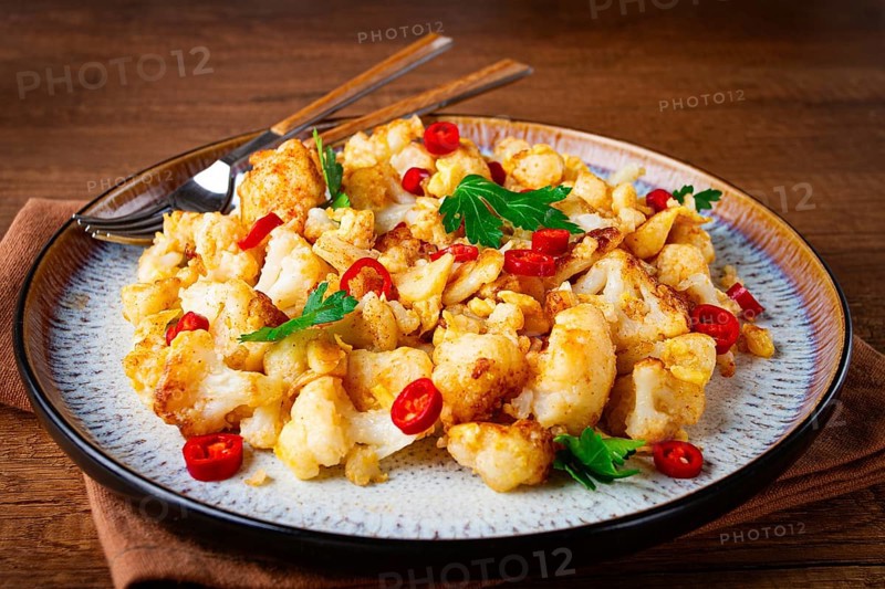 Spicy fried cauliflower served on a wooden countertop