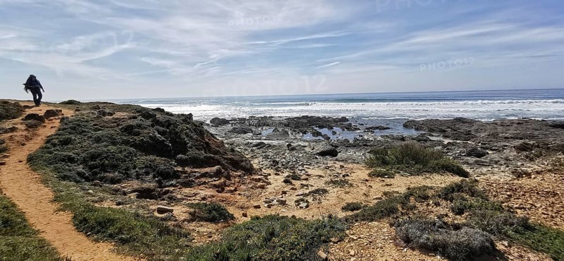 A hiker on a trail next to the rocky coast, Southwest Alentejo Natural Park and Vicentina Coast, Portugal