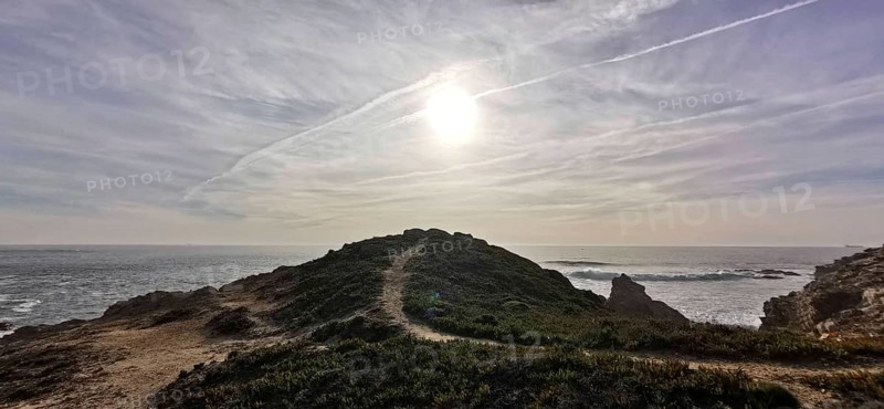 A trail leads over a hill, the sun shines over the coast, Southwest Alentejo nature park Park and Costa Vicentina, Portugal