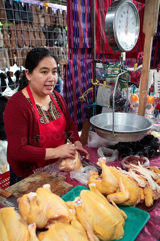 Mayan woman wearing traditional clothing with chicken meat and scales at the market in Sololá, Highlands, Sololá Department, Guatemala