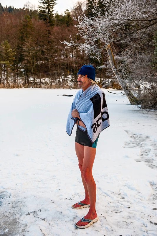 Man with cap, 55, standing on the ice wrapped in a towel after ice bathing, Thumsee, Bad Reichenhall, Berchtesgadener Land, Upper Bavaria, Bavaria, Germany