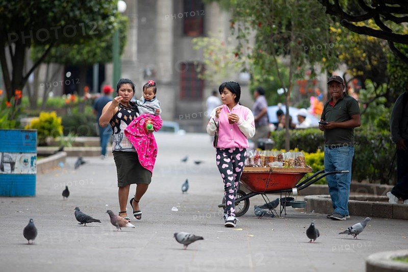 Guatemalan woman with toddlers in modern clothes stroll across Parque Centroamérica or Parque Central, Quetzaltenango or Xela, Quetzaltenango Province, Guatemala