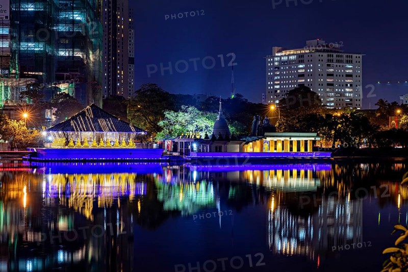 At night, a brightly lit temple is reflected in the calm waters of an urban lake, The Seema Malaka Temple in Colombo in Sri Lanka
