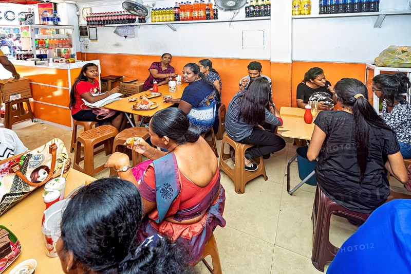 A busy restaurant where people sit at tables and talk, people in a simple restaurant in Colombo in Sri Lanka