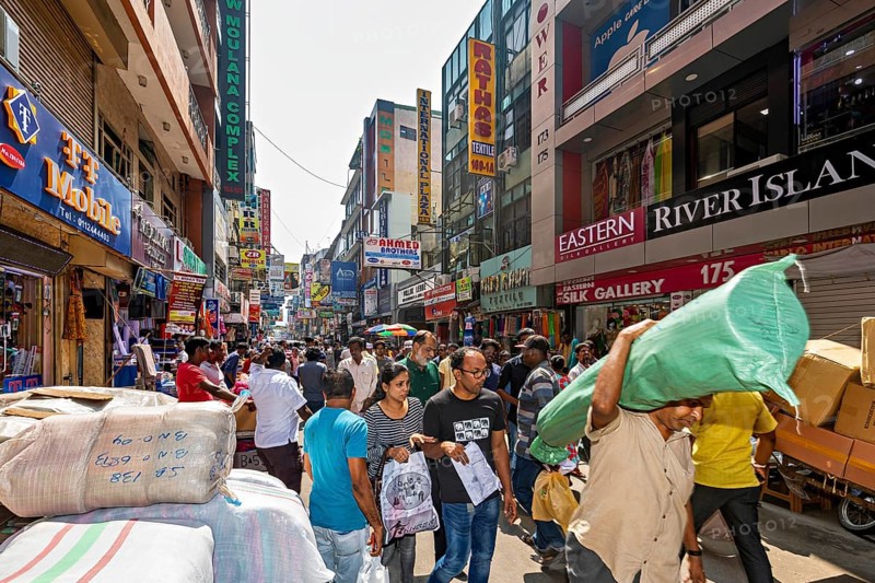 Well-visited shopping street with numerous people and payloads in bright sunlight, the hustle and bustle in the city center of Colombo in Sri Lanka