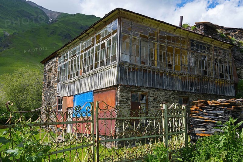 Old-fashioned house with a glass veranda against a mountain backdrop. Rustic atmosphere in green landscape, traditional house, Ushguli, Ushguli, Shibiani district, Zhibiani, Upper Svaneti, Svaneti, Georgia