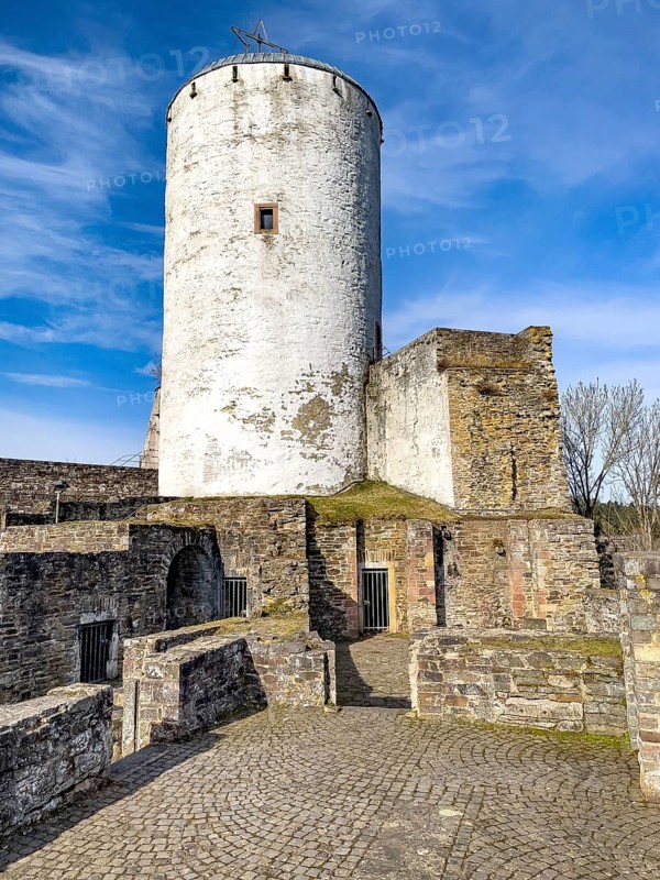 View of castle tower Bergfried made of stone masonry of castle ruins of medieval Höhenburg Reifferscheid Castle Excursion destination in Eifel, preserved foundations and remains of buildings restored in front of it, Reifferscheid, Hellenthal, Euskirchen district, North Rhine-Westphalia, Germany