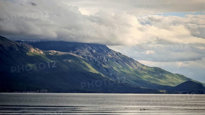 Dramatic mountain landscape with cloudy sky and calm lake in the foreground, Lake Ohrid, North Macedonia