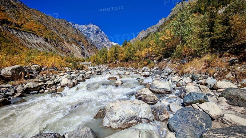 A rushing river in a mountainous fall landscape with clear blue sky, Mestia, Georgia