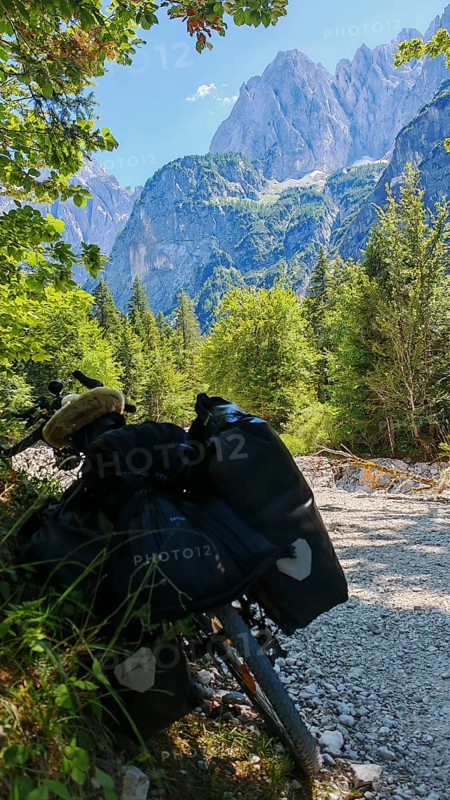 A bicycle on a dirt road in an alpine landscape with mountains and forests in the background, Slovenia