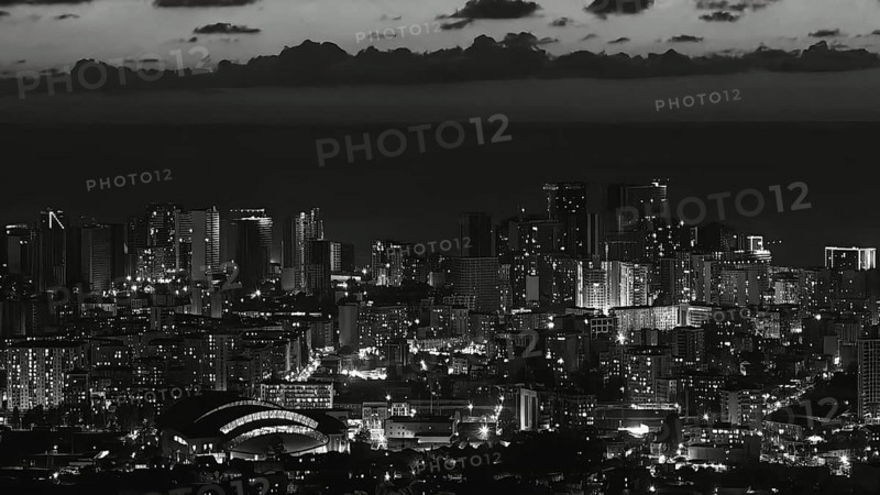 City view at night with illuminated skyscrapers and clouds in the sky in black and white, Batumi, Georgia