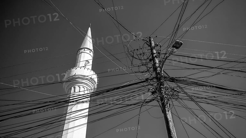 A minaret and numerous power lines against a monochrome sky, Prizren, Kosovo