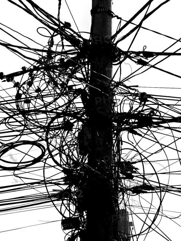 A power pole with a messy tangle of cables in an urban environment, black and white, Prizren, Kosovo