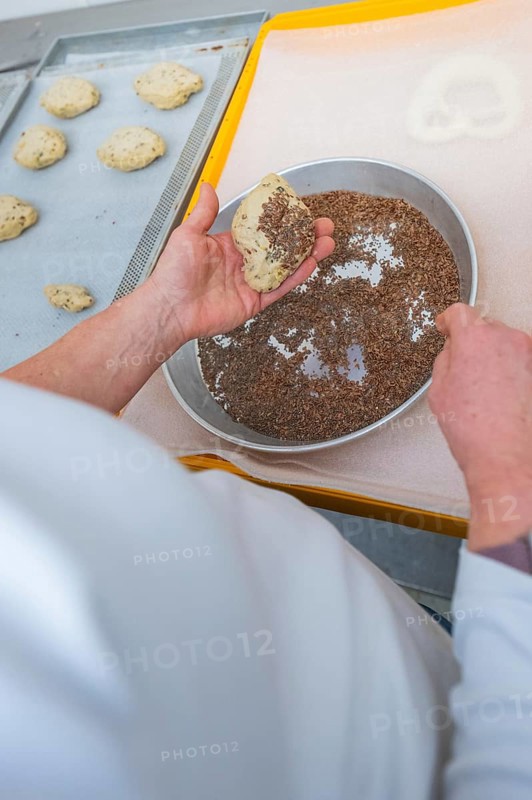 A baker prepares dough by sprinkling it with linseeds, baking rolls, Haselstaller Hof, Gechingen, Germany