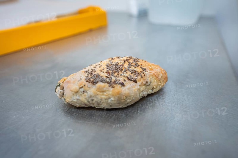 A roll with chia seeds is lying on a metal work surface in the bakery, bake rolls, Haselstaller Hof, Gechingen, Germany