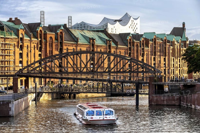 Ferry in front of bridge with warehouses in Hamburg's Speicherstadt, with the Elbe Philharmonic Hall in the background, Hamburg, Germany