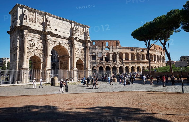 Arch of Constantine and Colosseum surrounded by tourists under blue sky, Rome, Lazio, Italy