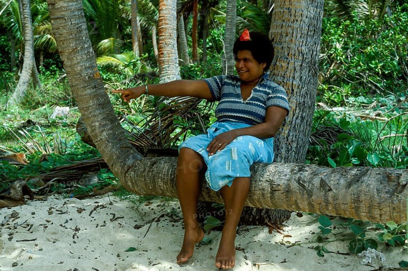 Woman sitting on a coconut trunk, (there are no chairs on Tavewa) Tavewa Island, Yasawa Islands, Fiji