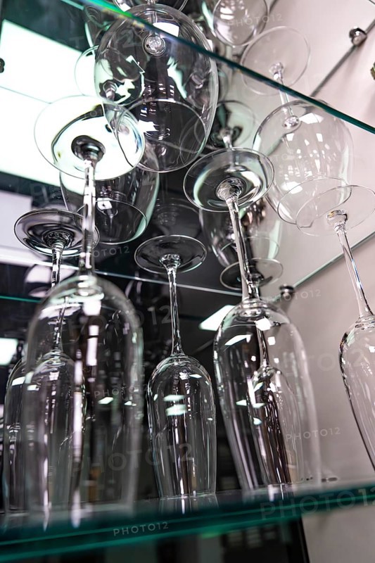 Showcase with elegant wine glasses on glass shelves