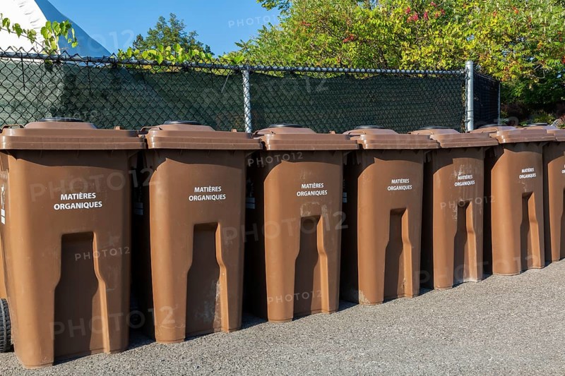 Row of brown plastic heavy duty portable composting bins for depositing organic materials and leftover foods at outdoor public recycling site, Quebec, Canada