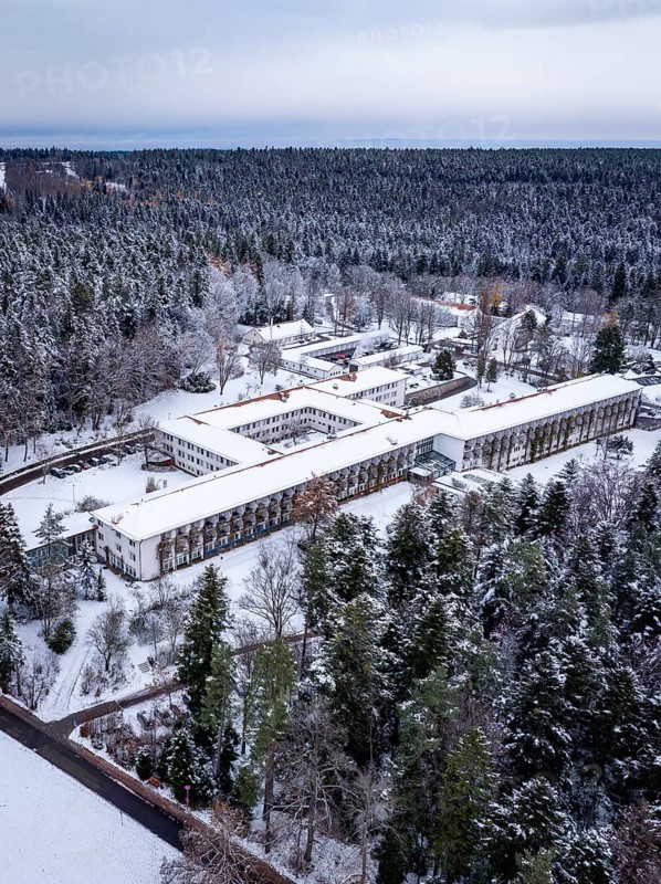 Aerial view of a snowy forest with a complex of buildings surrounded by pine trees, rehab clinic, Schömberg, Black Forest, Germany