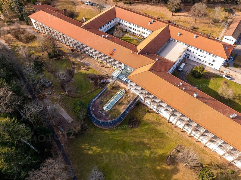 A building complex with a red roof and a spacious courtyard with green space from a bird's eye view, Rehab Clinic, Schömberg, Black Forest, Germany