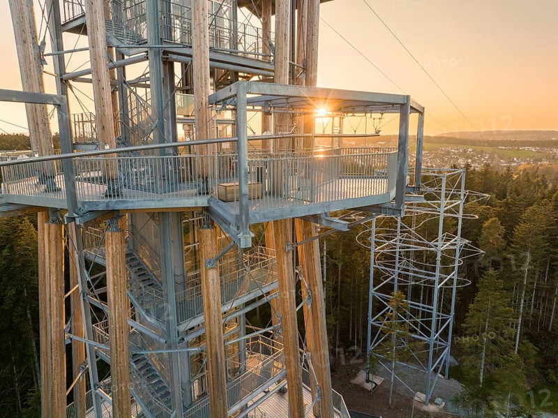 A wooden observation tower with metal structures at sunset, framed by a green forest, observation tower Himmelsglück with Flying Fox, Schömberg, Black Forest, Germany