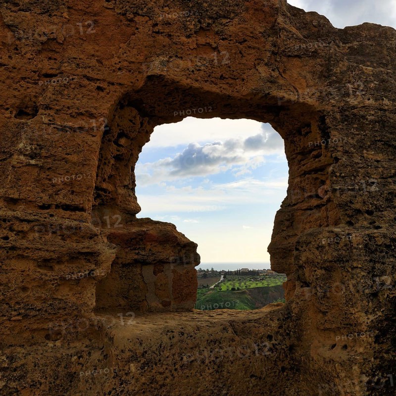 Arkosolium path, necropolis, view through arched niche on coastline and the sea, burial chamber, carved into the rock, wall, Valley of the Temples, Agrigento, Sicily, Italy